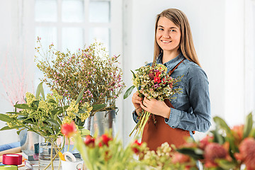 Image showing Florist at work: the young girl making fashion modern bouquet of different flowers