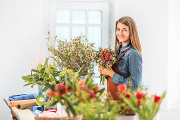 Image showing Florist at work: the young girl making fashion modern bouquet of different flowers