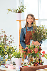 Image showing Florist at work: the young girl making fashion modern bouquet of different flowers