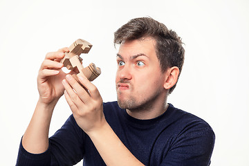 Image showing Attractive 25 year old business man looking confused with wooden puzzle.