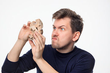 Image showing Attractive 25 year old business man looking confused with wooden puzzle.