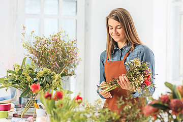 Image showing Florist at work: the young girl making fashion modern bouquet of different flowers