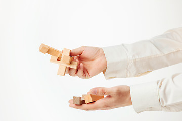 Image showing The toy wooden puzzle in hands solated on white background