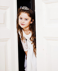 Image showing little cute girl at home, opening door well-dressed in white dress and tiara, adorable milk fairy teeth