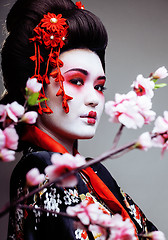 Image showing young pretty geisha in kimono with sakura and decoration