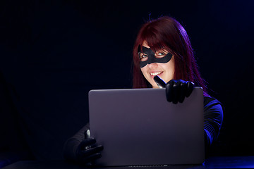Image showing Thief in mask holds laptop