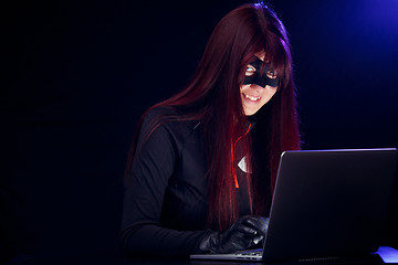 Image showing Smiling brunette thief with laptop