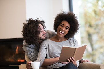 Image showing multiethnic couple hugging in front of fireplace