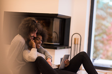 Image showing multiethnic couple using tablet computer on the floor