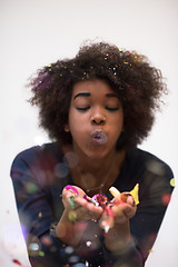 Image showing African American woman blowing confetti in the air