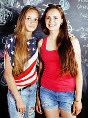 Image showing back to school after summer vacations, two teen real girls in classroom with blackboard painted together, lifestyle people concept