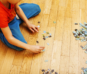 Image showing little kid playing with puzzles on wooden floor together with parent, lifestyle people concept, loving hands to each other 