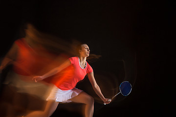 Image showing Young woman playing badminton over black background