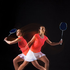 Image showing Young woman playing badminton over black background