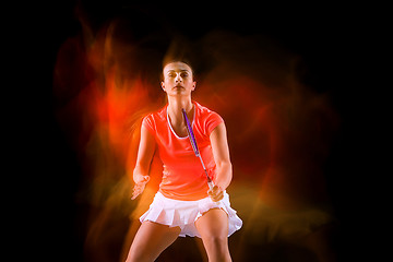 Image showing Young woman playing badminton over black background