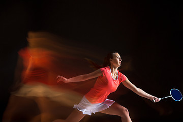 Image showing Young woman playing badminton over black background