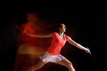 Image showing Young woman playing badminton over black background