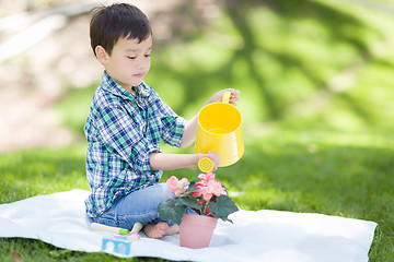 Image showing Mixed Race Young Boy Watering His Potted Flowers Outside On The 