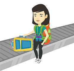 Image showing Woman picking up suitcase on luggage conveyor belt