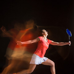 Image showing Young woman playing badminton over black background
