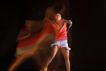 Image showing Young woman playing badminton over black background