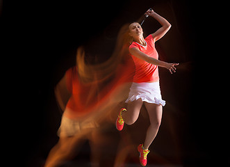 Image showing Young woman playing badminton over black background