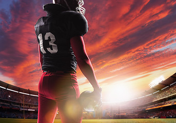 Image showing American football player posing with ball on stadium background