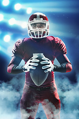 Image showing American football player posing with ball on stadium background