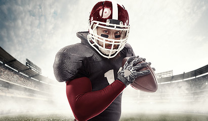 Image showing American football player posing with ball on stadium background