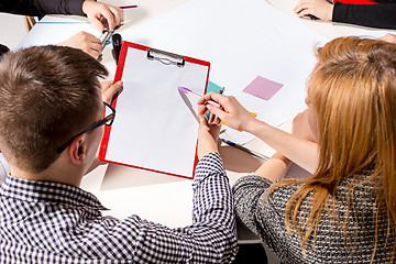 Image showing Team sitting behind desk, checking reports, talking.