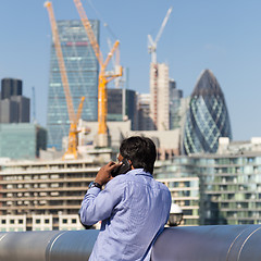 Image showing International businessman talking on mobile phone outdoor in London city, UK.