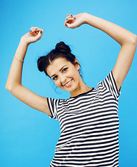 Image showing young pretty teenage modern hipster girl posing emotional happy smiling on blue background, lifestyle people concept 