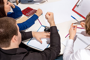 Image showing Team sitting behind desk, checking reports, talking.