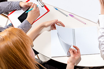 Image showing The woman sitting behind desk, checking reports, talking.