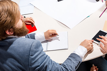 Image showing The man sitting behind desk, checking reports, talking.