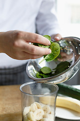 Image showing Crop hands making fresh smoothie