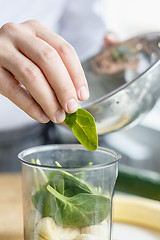 Image showing Crop hands making fresh smoothie