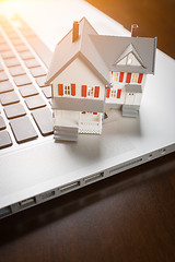 Image showing Miniature House And Laptop Computer Resting on Desktop.