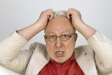 Image showing White haired senior with glasses tearing his hair