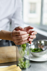 Image showing Crop hands pouring cut celery in container