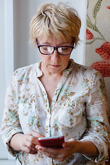 Image showing Mature woman in glasses using device