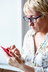 Image showing Mature female in glasses using smartphone