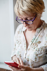 Image showing Mature female in glasses using smartphone