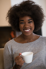 Image showing black woman drinking coffee in front of fireplace