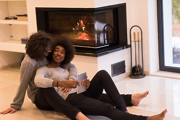 Image showing multiethnic couple using tablet computer on the floor