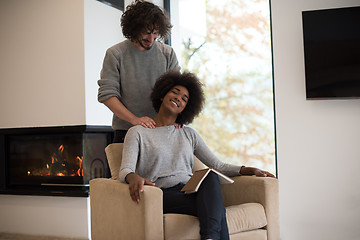 Image showing multiethnic couple hugging in front of fireplace