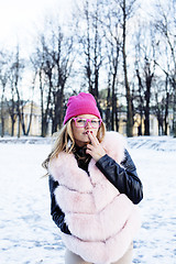 Image showing young pretty teenage hipster girl outdoor in winter snow park having fun drinking coffee, warming up happy smiling, lifestyle people concept