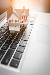 Image showing Miniature House And Laptop Computer Resting on Desktop.