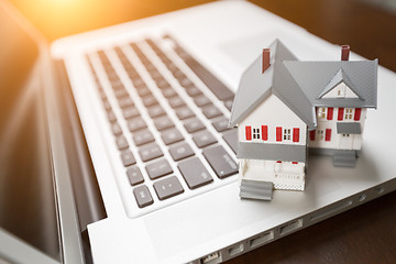 Image showing Miniature House And Laptop Computer Resting on Desktop.