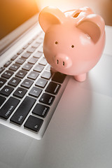 Image showing Piggy Bank Resting on Laptop Computer Keyboard.